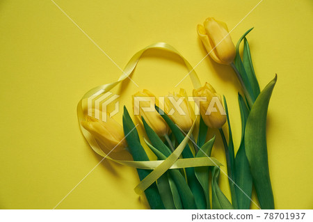 Five yellow tulips on a yellow background with the heart made of ribbon. Five yellow tulips on a yellow background with the heart made of ribbon. 78701937