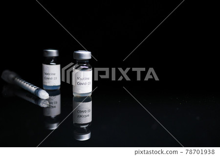 Close up of coronavirus vaccine and syringe on black background Close up of coronavirus vaccine and syringe on black background 78701938