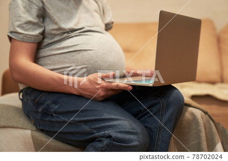 Pregnant woman at home is sitting with computer, online shopping or home office Pregnant woman at home is sitting with computer, online shopping or home office 78702024