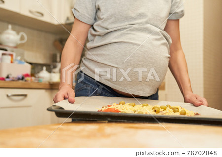 Pregnant woman holds on a baking sheet prepared for baking pizza.Cooking at home Pregnant woman holds on a baking sheet prepared for baking pizza.Cooking at home 78702048