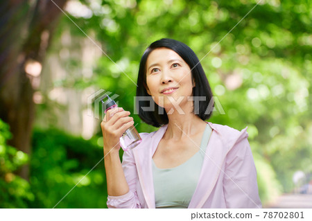 Middle woman drinking water in sportswear in the green 78702801