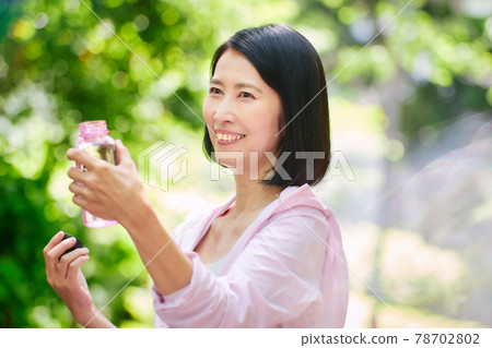 Middle woman drinking water in sportswear in the green 78702802
