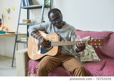 Man playing guitar at home 78703056