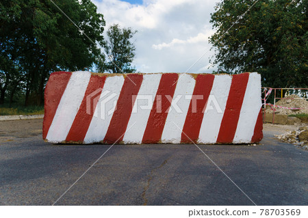 concrete block with red and white striped lines as a roadblock, traffic is prohibited and road works, the road is closed for maintenance concrete block with red and white striped lines as a roadblock, traffic is prohibited and road works, the road is closed for maintenance 78703569