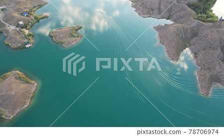 A speedboat sails along the strait at sunset. 78706974