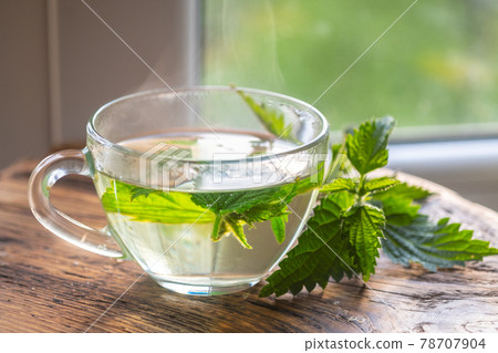 Transparent cup with nettle tea. fresh nettle on a wooden board. 78707904