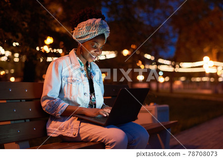 Woman working on laptop in the park 78708073