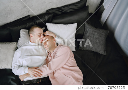 Happy gay couple lying on bed at home 78708225