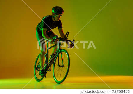 Cyclist riding a bicycle isolated against neon background Cyclist riding a bicycle isolated against neon background 78708495