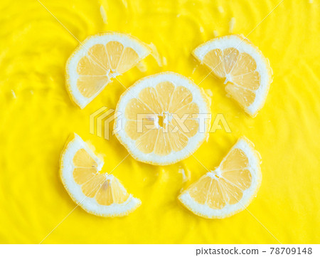 Intense yellow lemon citrus slice in water with ripples texture summer background Intense yellow lemon citrus slice in water with ripples texture summer background 78709148