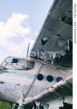 Close-up of a crashed airplane wing. The metal frame and internal parts are visible. Pieces of upholstery and fabric upholstery blow in the wind. Rust and debris Close-up of a crashed airplane wing. The metal frame and internal parts are visible. Pieces of upholstery and fabric upholstery blow in the wind. Rust and debris 78710168