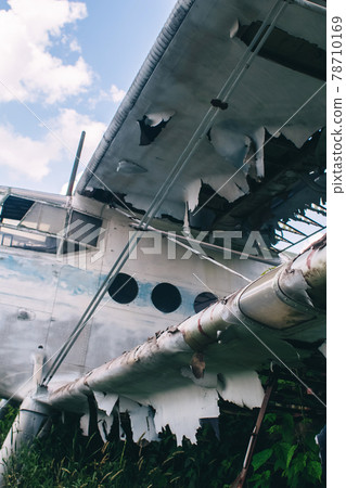 Close-up of a crashed airplane wing. The metal frame and internal parts are visible. Pieces of upholstery and fabric upholstery blow in the wind. Rust and debris Close-up of a crashed airplane wing. The metal frame and internal parts are visible. Pieces of upholstery and fabric upholstery blow in the wind. Rust and debris 78710169