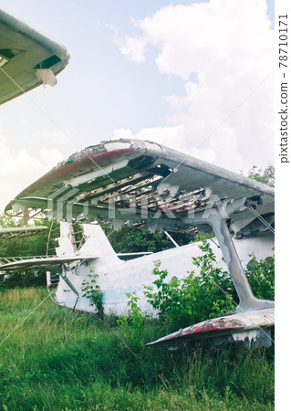 Close-up of a crashed airplane wing. The metal frame and internal parts are visible. Pieces of upholstery and fabric upholstery blow in the wind. Rust and debris Close-up of a crashed airplane wing. The metal frame and internal parts are visible. Pieces of upholstery and fabric upholstery blow in the wind. Rust and debris 78710171