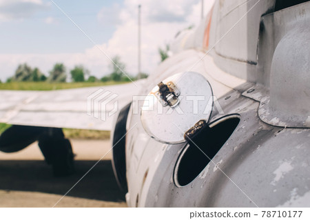 Close-up of part of the fuselage of an old military fighter jet, which has an open fuel system. The open tank of the aircraft, the metal cover is clearly visible 78710177
