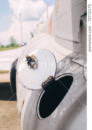 Close-up of part of the fuselage of an old military fighter jet, which has an open fuel system. The open tank of the aircraft, the metal cover is clearly visible 78710178