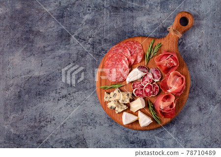 Serving board with meat and cheese snacks. 78710489