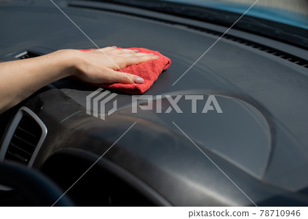 Woman wipes the car dashboard from dust. 78710946