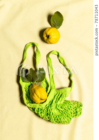 Two quince apple fruits in green mesh bag on linen Two quince apple fruits in green mesh bag on linen 78711043