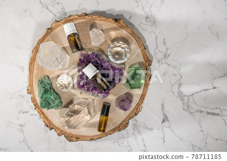 Flat lay of essential oil bottles, beautiful crystals and gemstones on wooden plate on marble background Flat lay of essential oil bottles, beautiful crystals and gemstones on wooden plate on marble background 78711185