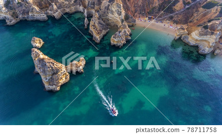 Camilo Beach in Lagos, Algarve - Portugal. Portuguese southern golden coast cliffs. Tourists on the beach. Sunny day aerial view. Camilo Beach in Lagos, Algarve - Portugal. Portuguese southern golden coast cliffs. Tourists on the beach. Sunny day aerial view. 78711758