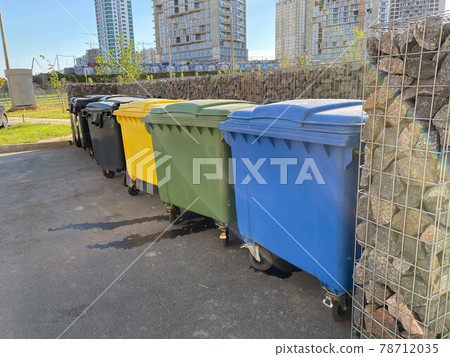 Black, yellow, green and blue plastic large modern containers for separate collection and subsequent ecological recycling of waste in a new area of the city Black, yellow, green and blue plastic large modern containers for separate collection and subsequent ecological recycling of waste in a new area of the city 78712035