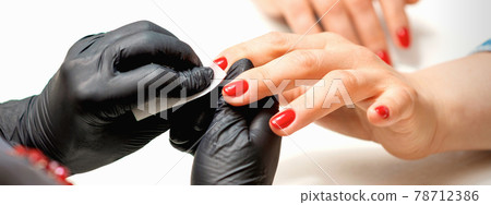 Manicurist wiping nails with napkin Manicurist wiping nails with napkin 78712386