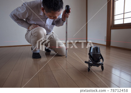 Workers measuring floor height with a laser marking device Workers measuring floor height with a laser marking device 78712458