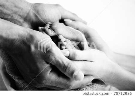 Children's feet in hold hands of mother and father on white. Mother, father and newborn Child. Happy Family people concept. Black and white. 78712986