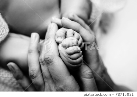 Children's feet in hold hands of mother and father on white. Mother, father and newborn Child. Happy Family people concept. Black and white. 78713051