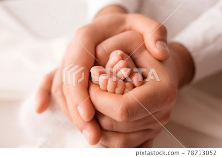 Tiny feet of a newborn child in the hands of a parent. One week old baby. The image of the first days of life.  78713052