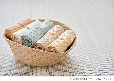 Collection of natural muslin bath towels in a wicker basket on the floor. Natural, soft, air and stylish home textiles. 78713775