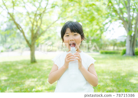 A girl drinking water with a smile A girl drinking water with a smile 78715386
