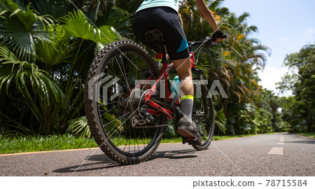 Woman riding a bike on tropical park trail in summer 78715584