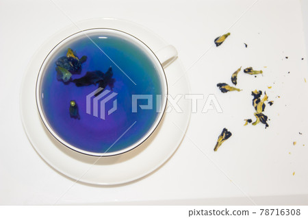 The mood color is blue - blue tea in a white mug, which stands on a white saucer and a white tray. The mood color is blue - blue tea in a white mug, which stands on a white saucer and a white tray. 78716308