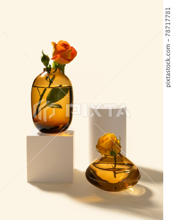 Roses in glass vases and white cylinder and cube podiums on beige background with hard long shadows front view, vertical. Minimalist creative composition Roses in glass vases and white cylinder and cube podiums on beige background with hard long shadows front view, vertical. Minimalist creative composition 78717781