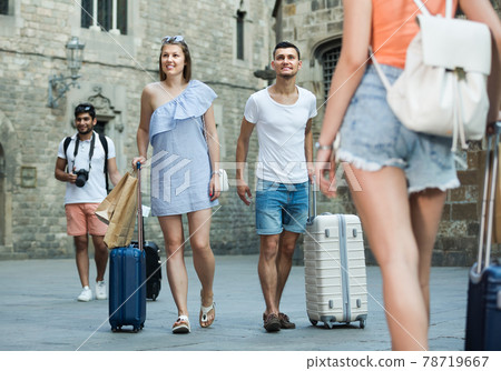 Smiling traveling couple taking promenade with suitcases 78719667