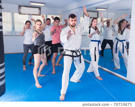 adults attempting to master new moves during karate class 78719873