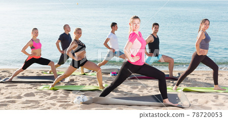 People practicing yoga on beach 78720053