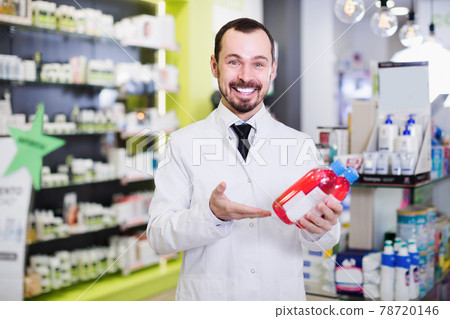 Smiling man pharmacist showing right pills 78720146