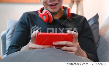 Cropped shot happy man lying on sofa and using mobile phone. 78722695