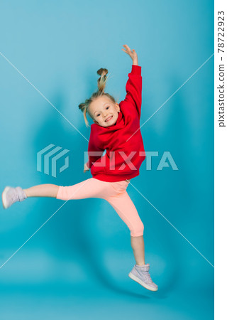 Portrait of a cheerful girl jumping and dancing against a studio background Portrait of a cheerful girl jumping and dancing against a studio background 78722923