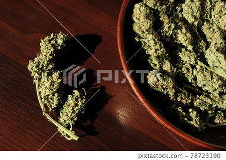 Marijuana buds storage. Medicinal cannabis flowering on brown wooden background, isolated. 78723190
