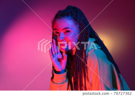 Caucasian young woman's portrait on dark studio background in neon. Concept of human emotions, facial expression. 78727362