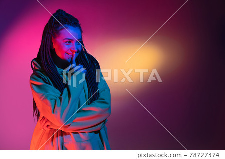 Caucasian young woman's portrait on dark studio background in neon. Concept of human emotions, facial expression. Caucasian young woman's portrait on dark studio background in neon. Concept of human emotions, facial expression. 78727374