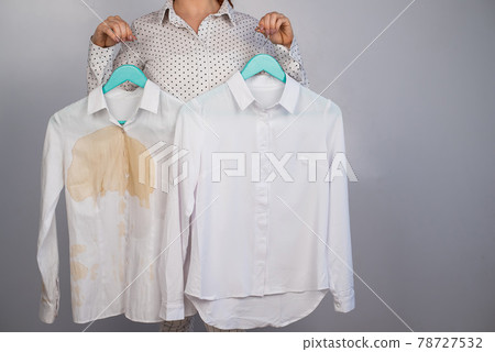 A woman compares two white shirts before and after washing. The girl is holding one blouse, clean and ironed, and the other, dirty with coffee stains 78727532