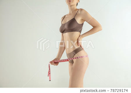 The girl taking measurements of her body, white background. The girl taking measurements of her body, white background. 78729174