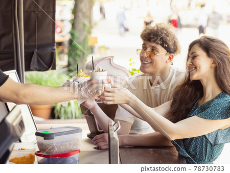 Happy attractive young couple romantically eating a fresh pizza outdoors. 78730783