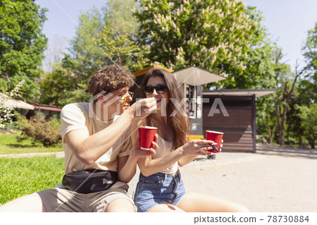 Happy attractive young couple romantically eating a fresh pizza outdoors. 78730884