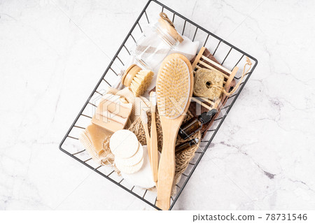 Basket with Natural bathroom and home spa tools. Zero waste concept. Bamboo toothbrush, natural soap bar, cotton pads, brush, homemade beauty products in reusable bottles on white marble background Basket with Natural bathroom and home spa tools. Zero waste concept. Bamboo toothbrush, natural soap bar, cotton pads, brush, homemade beauty products in reusable bottles on white marble background 78731546