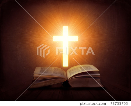 Open book with glowing cross above it; religion concept 78735793